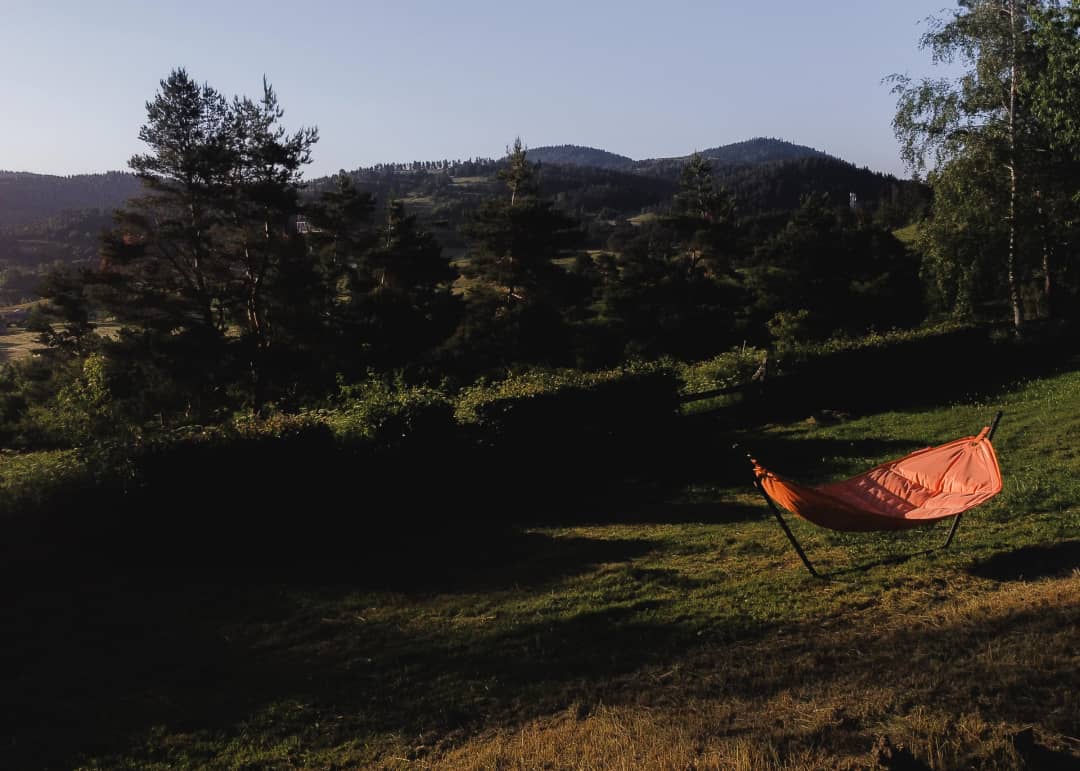 Une prairie avec un hamac et les montagnes dans les derniers rayons du soleil