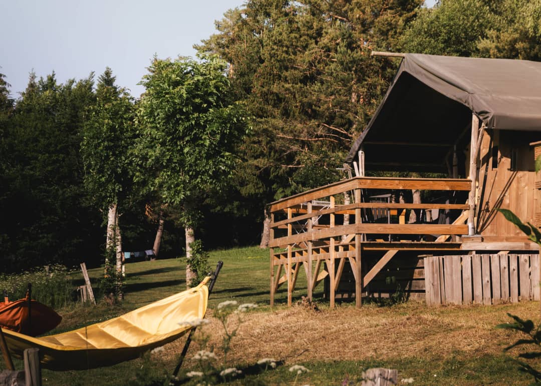 Base Lodge avec une terrasse en bois et un hamac parmi les arbres