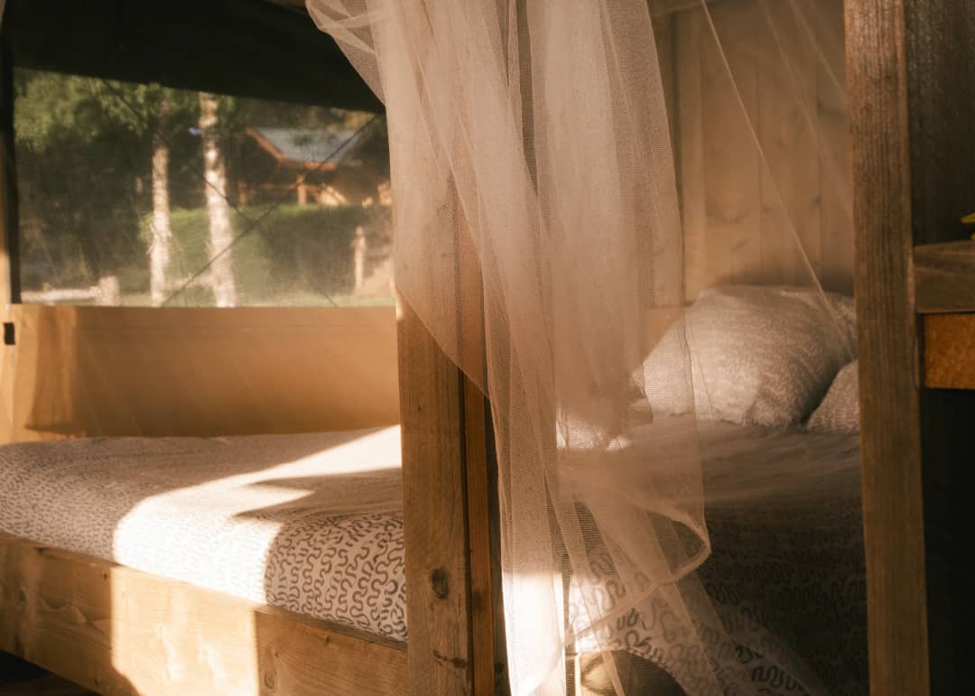 Un lit derrière la moustiquaire, à la lumière du matin