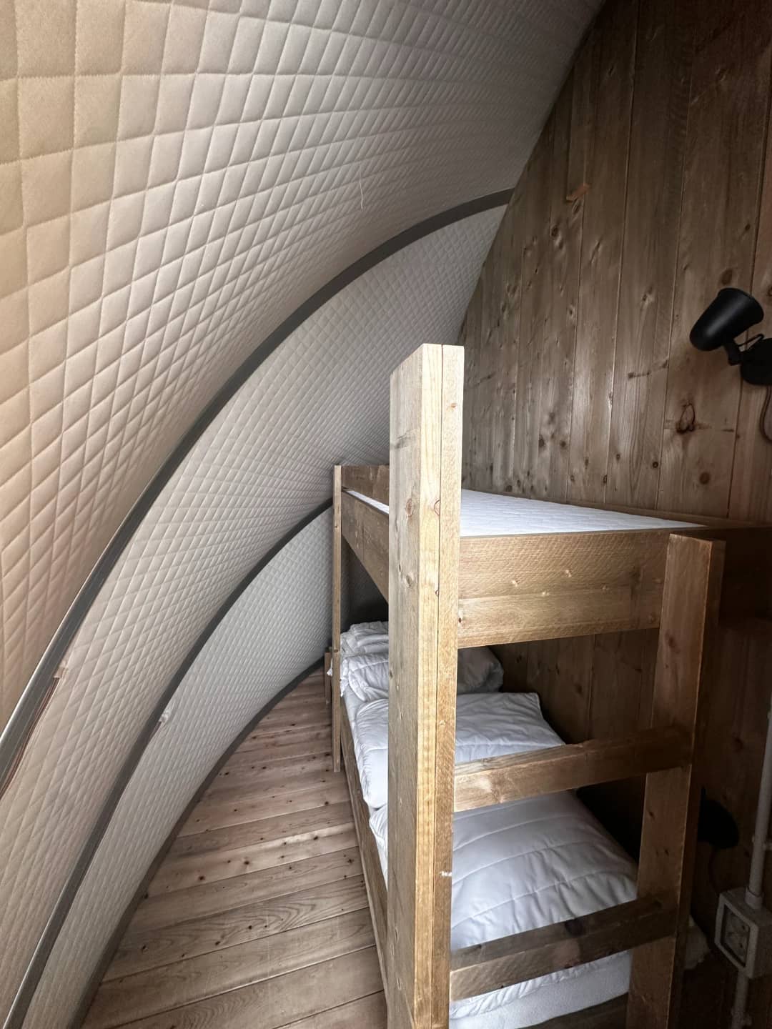 Lits superposés en bois avec literie blanche sous la paroi rembourrée et incurvée du Big Oak Lodge XL